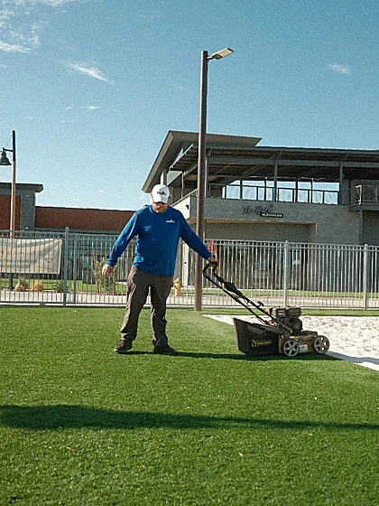 Technician grooming the artificial turf lawn beside the bar deck at Revel Surf
