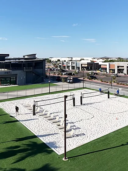 Sand volleyball courts ringed by artificial turf walkways and lounge decks at Revel Surf in Mesa, Arizona