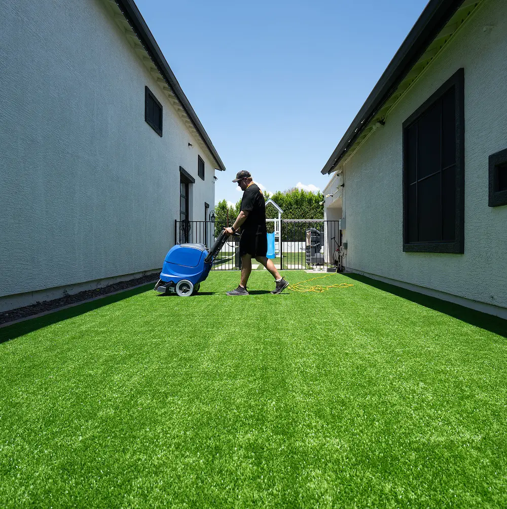 Squeaky Clean Turf technician deep-cleaning a residential artificial lawn in Arizona